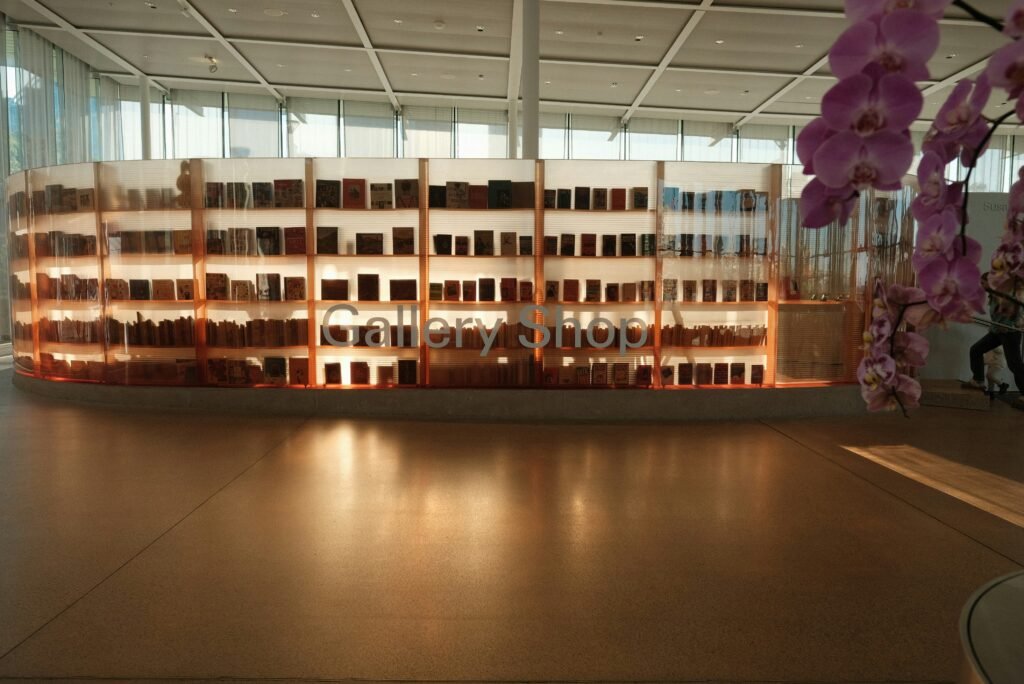 Backlit gallery shop display in a museum, lined with books and merchandise