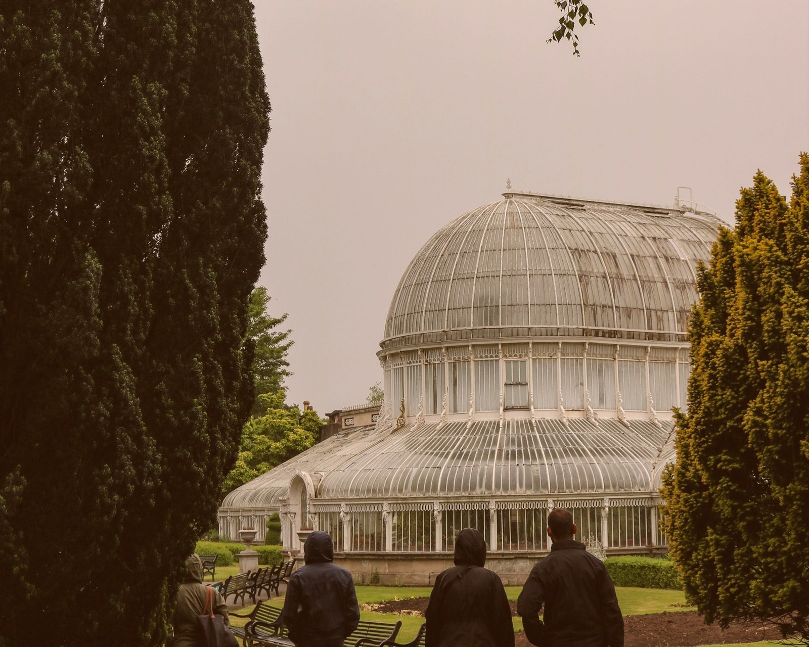 Visitors looking towards a Victorian glasshouse in a botanical garden