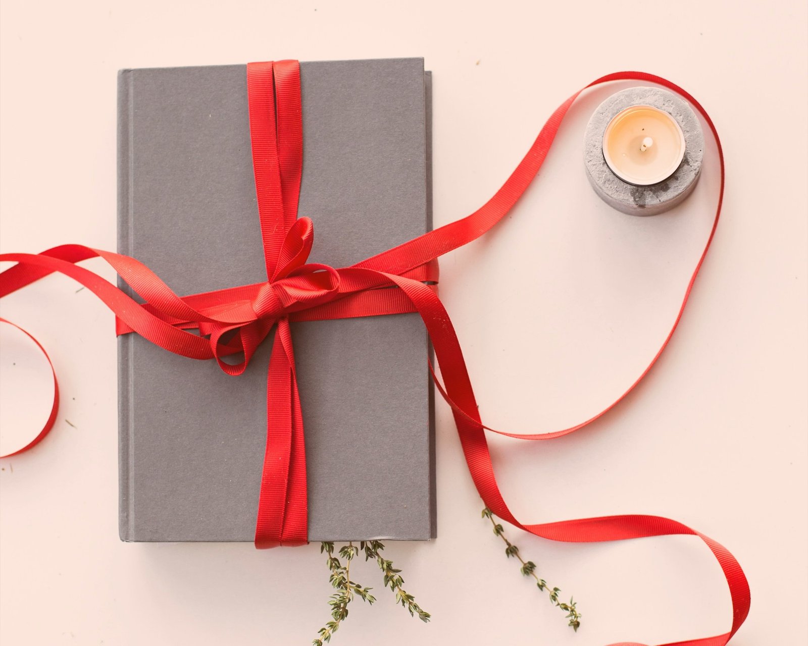 Gift wrapped in red ribbon beside a lit candle