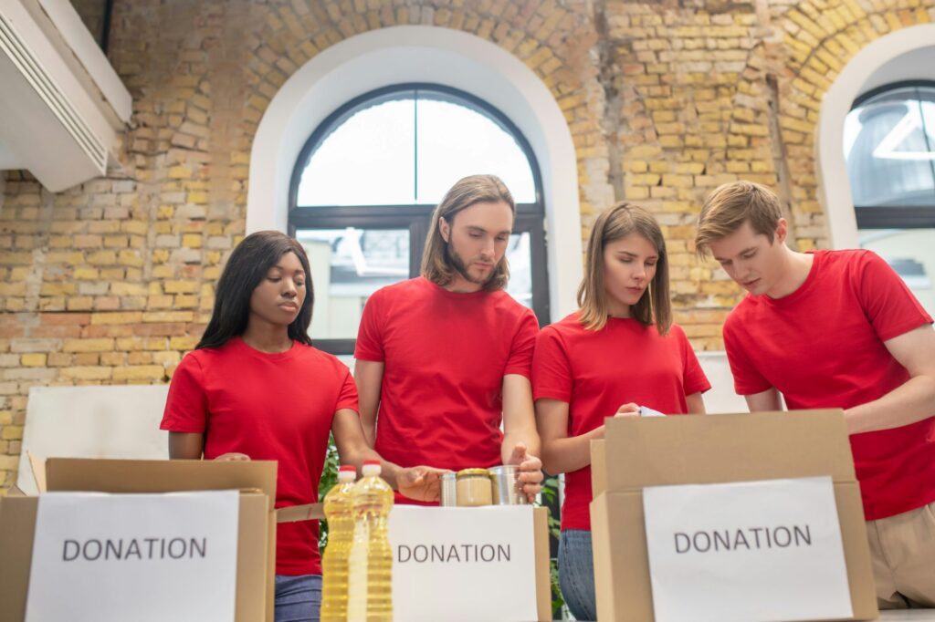 Four volunteers in matching red T-shirts packing donation boxes