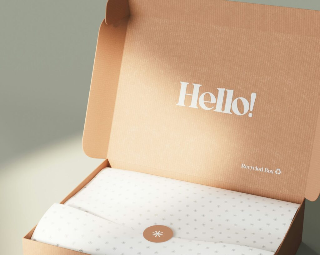 Open shipping box printed with Hello, lined with tissue paper and a sticker seal